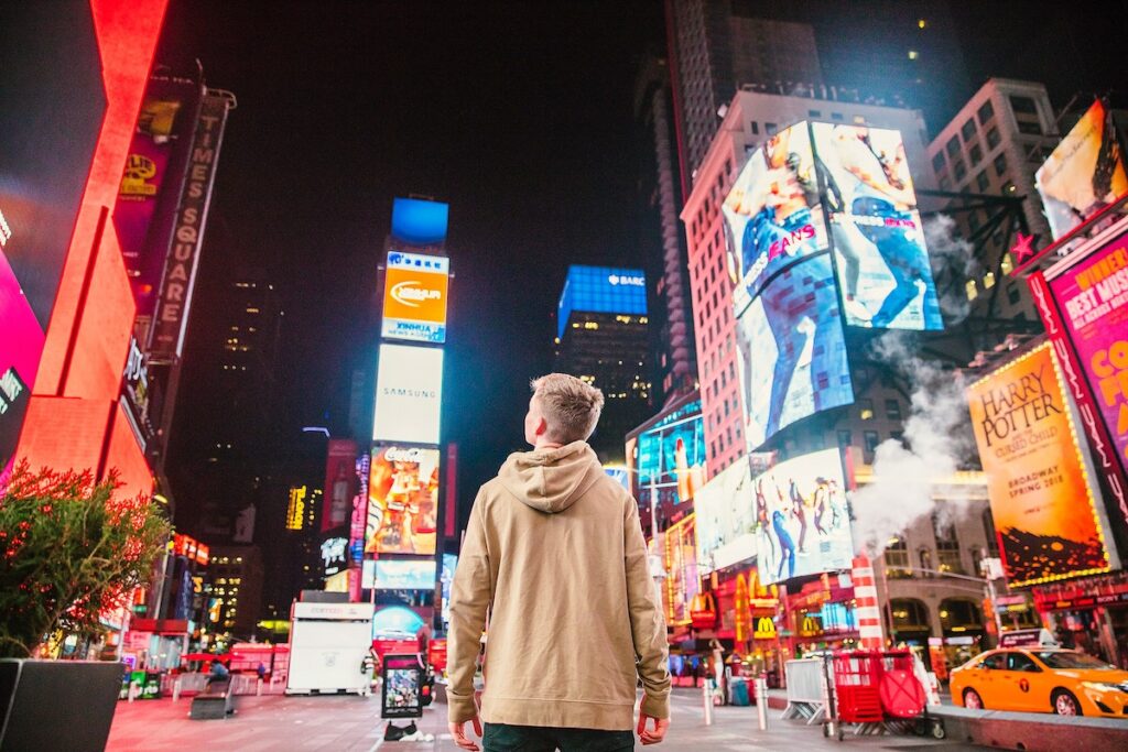 Young man in Times Square looking at neon signs